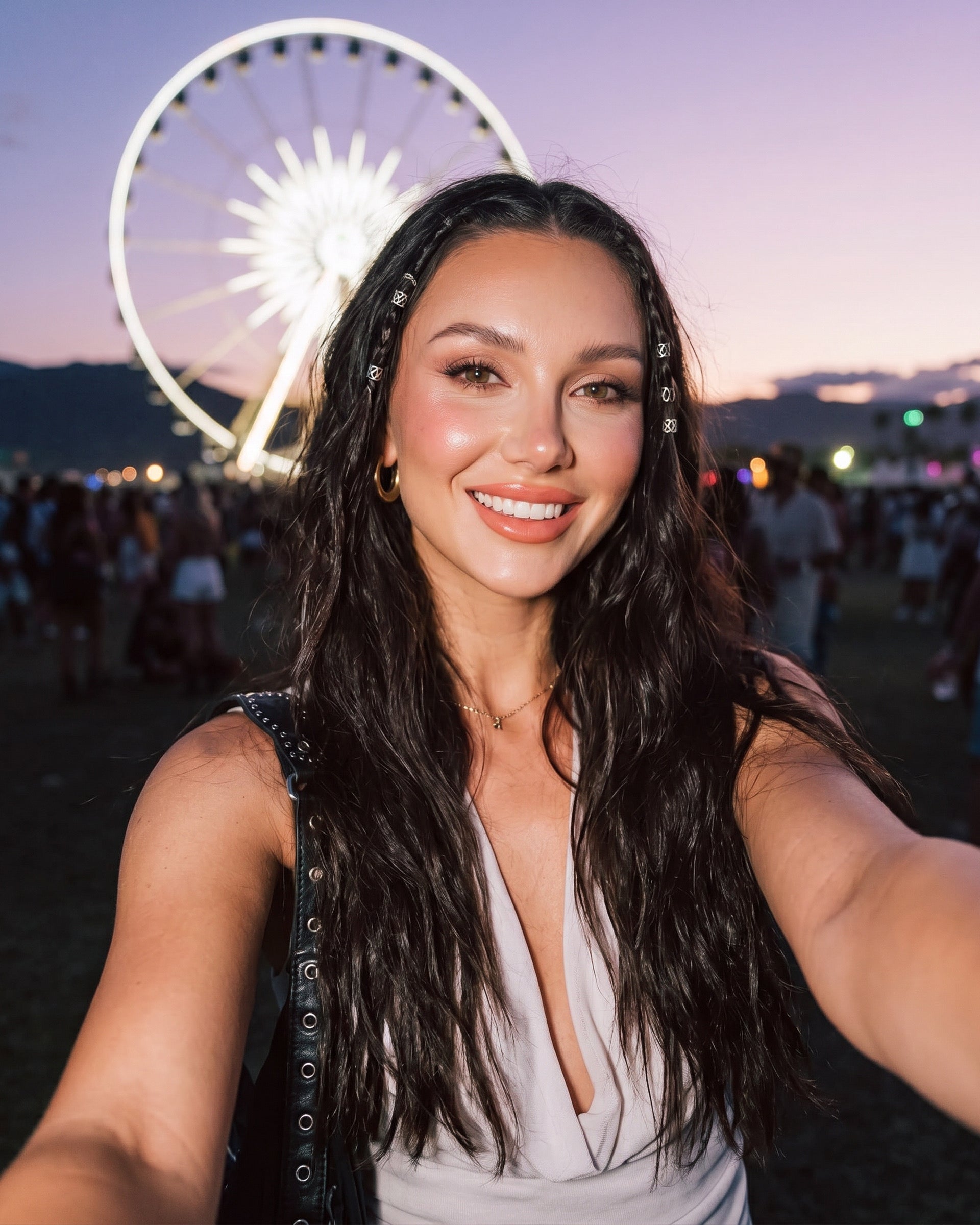 Smiling woman taking a selfie at Coachella during sunset, with CoreLash lash clusters and glowing makeup, styled waves, and the iconic ferris wheel lit up in the background.